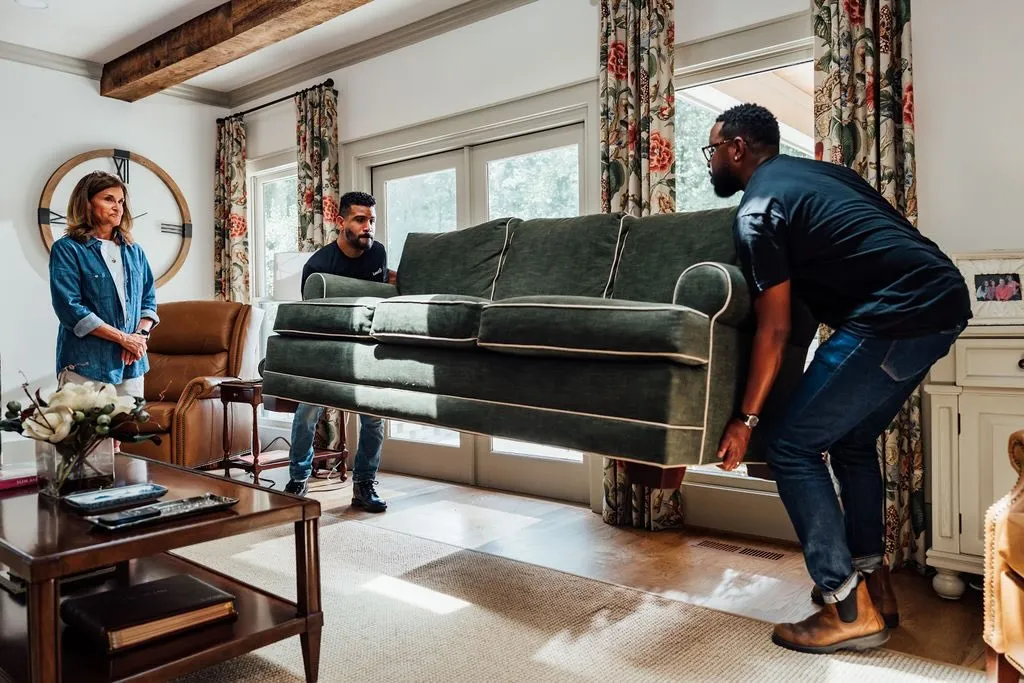 Two MovR movers carrying a sofa through a living room